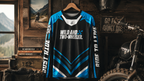 Motorcycle jersey with text on a hanger against a rustic background with a motorcycle and scenic view.