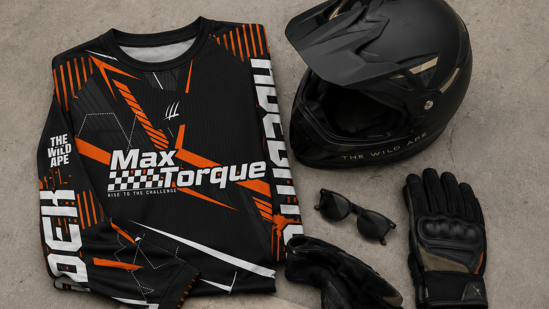 Motorcycle gear including a jersey, helmet, gloves, sunglasses, and keys on a concrete floor.